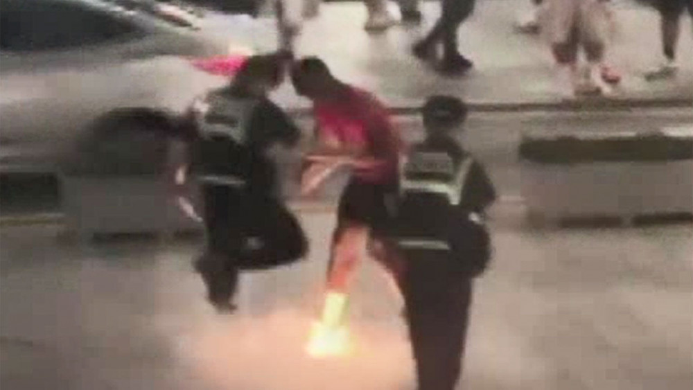 경찰과 실랑이를 벌이다 발밑으로 불꽃을 쏘는 외국인 남성